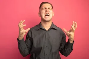 young handsome man grey shirt shouting with raised arms angry crazy mad standing pink wall 141793 52844